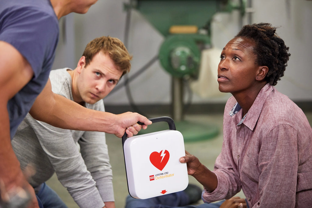 Man handing an AED to woman